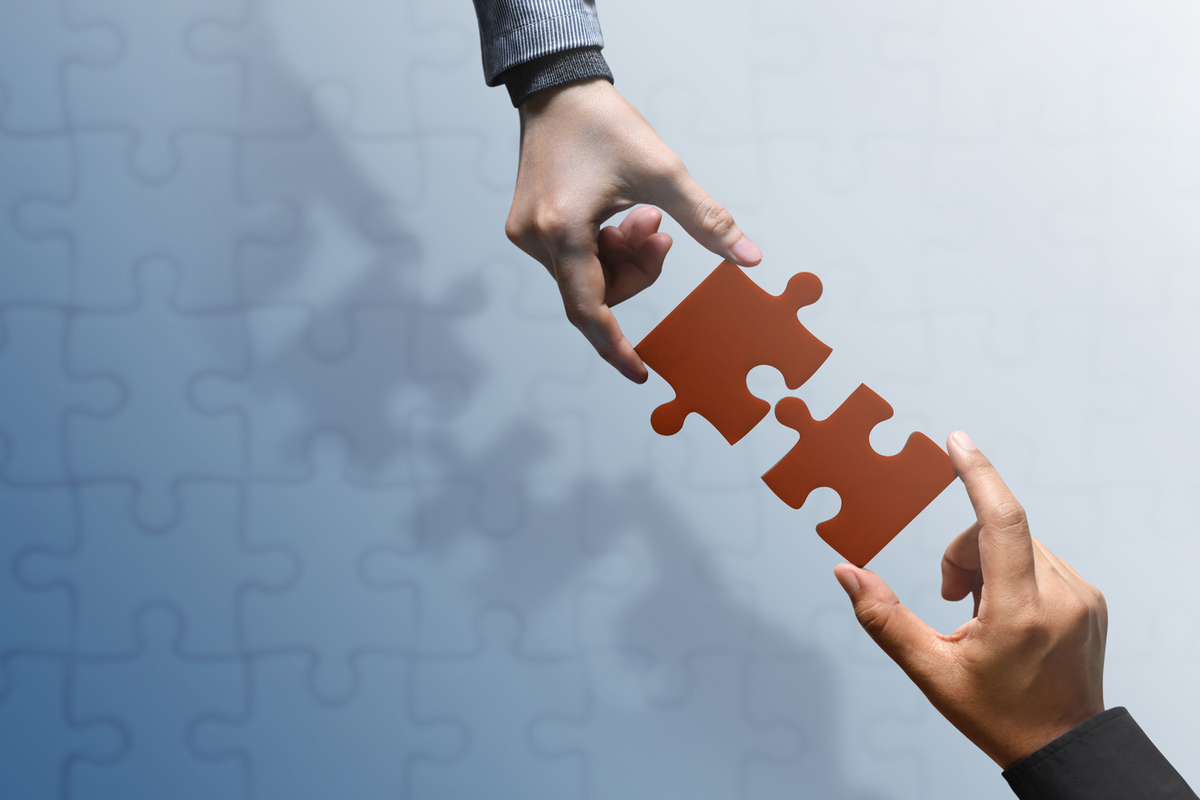 Business Partnership or Teamwork Concept. Hands of two People Try to Fit or Conncet Jigsaw Puzzle Piece Together. Top View
